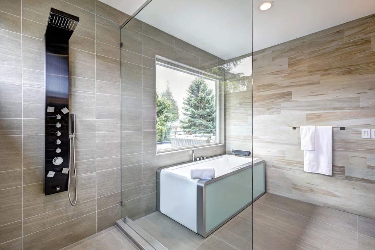 Salle de bains moderne luxueuse avec baignoire îlot blanche rectangulaire, cabine de douche vitrée à l'italienne équipée d'une colonne de douche thermostatique noire multi-jets