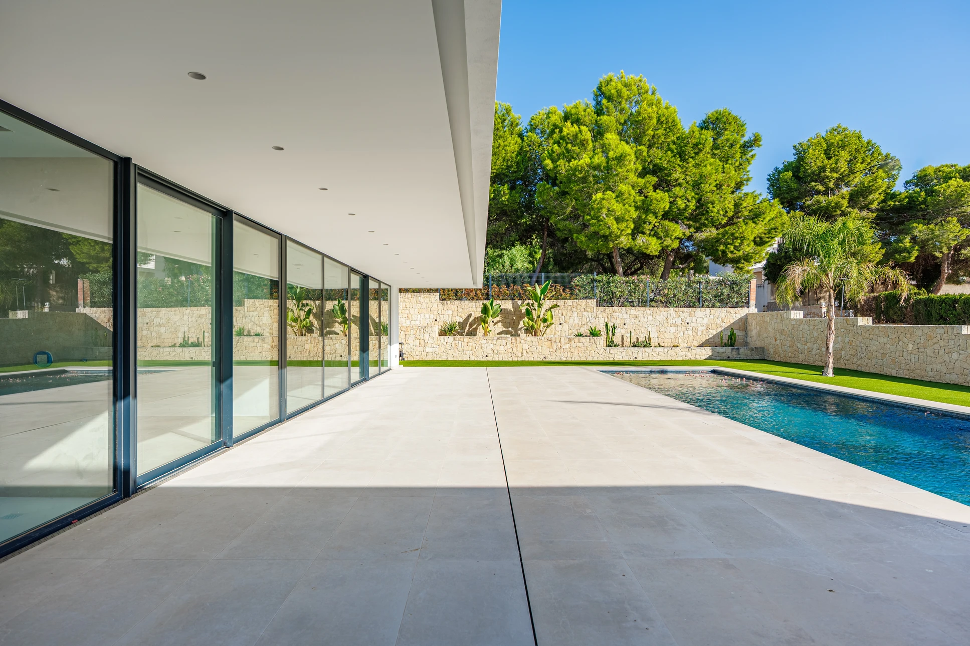 Terrasse moderne sur toit avec mobilier d'extérieur en résine tressée, coussins bleus et blancs, tables basses rondes