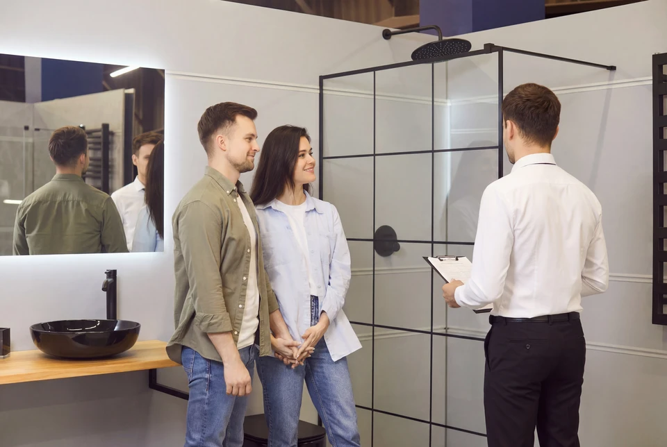 Couple souriant clients et directeur de vente montrant aux clients douche de salle de bain moderne, famille heureuse faisant l'achat, choisissant la cabine de douche, ustensiles pour la salle de bain à la maison, aide du vendeur de plomberie, conseil